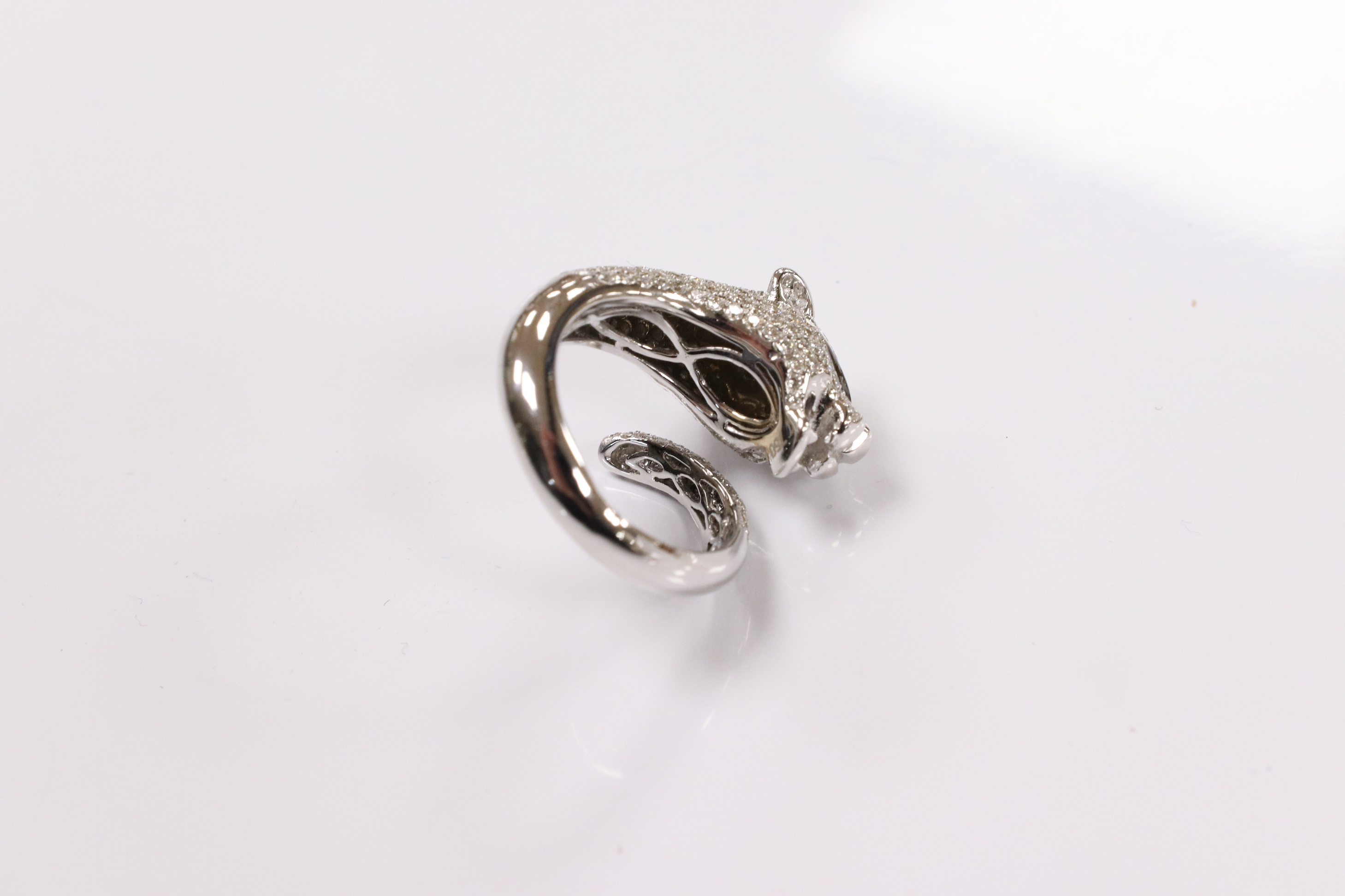 A modern Cartier style 18k white metal and pave set diamond chip dress ring, modelled as the head and tail of a leopard, size M, gross 9 grams. Condition - good